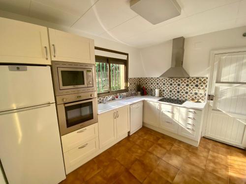 cocina con armarios blancos y nevera blanca en Casa Palau - Relax y naturaleza a los pies del Montseny Arbúcies en Arbúcies