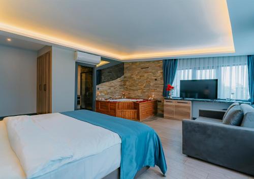 a bedroom with a bed and a couch and a television at City Port Hotel Trabzon in Trabzon