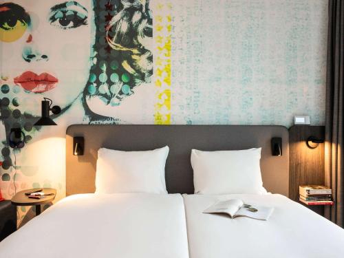 a bedroom with two beds and a painting on the wall at ibis Styles Delft City Centre in Delft