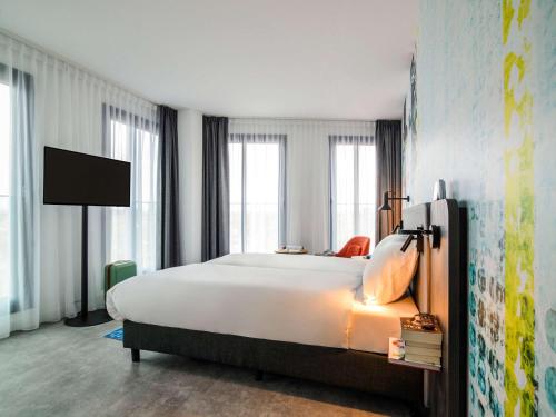 a bedroom with a large white bed and windows at ibis Styles Delft City Centre in Delft