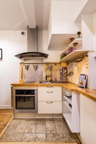 une cuisine avec des armoires blanches et une cuisinière dans l'établissement very cozy 2p Louvre--Orsay-- saint-germain-des-pres, à Paris