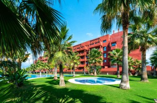 a hotel with palm trees in front of a building at Alojamiento Apartamento Motril Playa Granada campo golf in Motril