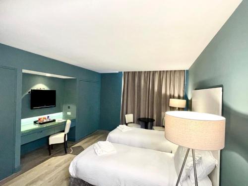 a hotel room with two beds and a desk at Axiom Park Hotel in London