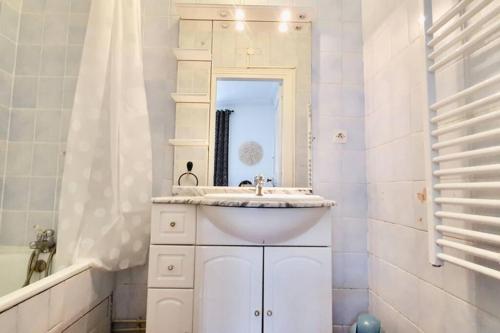 a white bathroom with a sink and a mirror at Beau 2 pièces en centre ville et à 200m de la mer in Cabourg