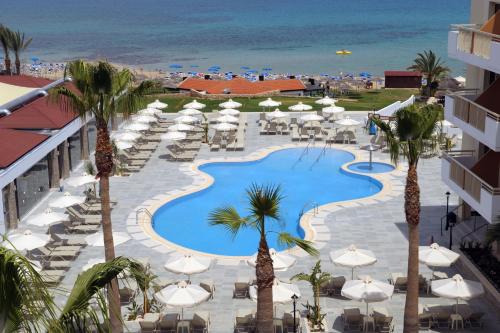 a view of a pool with umbrellas and chairs and the ocean at Golden Star Beach in Protaras
