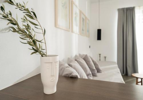 a white vase sitting on a table with a plant at SOPHID Wellness Suites Karpathos in Karpathos