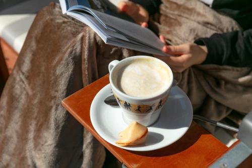 a person reading a magazine next to a cup of coffee at Hotel Bethanien in Langeoog