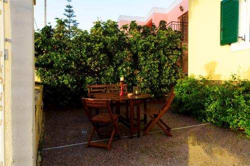 a wooden table and two chairs sitting next to a hedge at JASMINE OF POSEIDONIA in Posidhonía