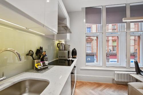 cocina con fregadero y 2 ventanas en Victoria House by Q Apartments, en Reading