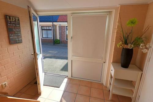 une porte menant à un couloir avec un vase sur une table dans l'établissement Zomerhuis At Sea op top locatie in Egmond aan zee, à Egmond aan Zee
