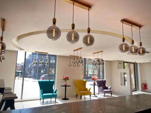 a lobby with colorful chairs and pendant lights at Axiom Park Hotel in London