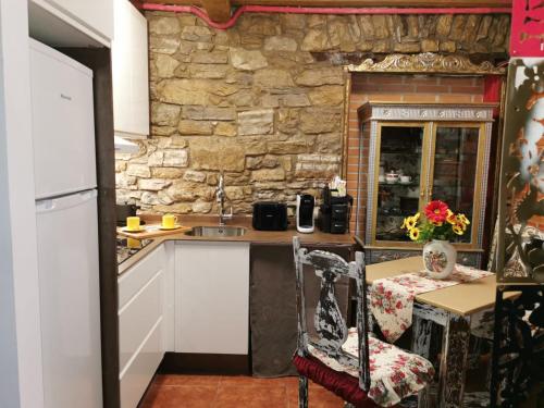 a kitchen with white cabinets and a stone wall at Apartamento turístico Somió in Gijón