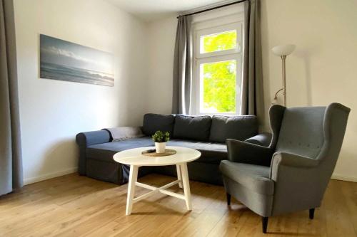 een woonkamer met een bank, een tafel en een stoel bij Villa Meeresgruss FeWo 9 in Ostseebad Sellin