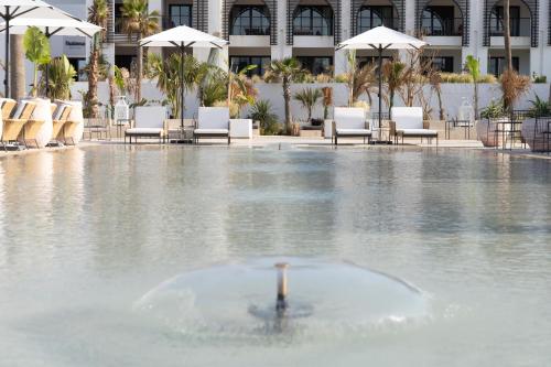 a fountain in a pool with chairs and umbrellas at Sofitel Agadir Thalassa Sea & Spa in Agadir