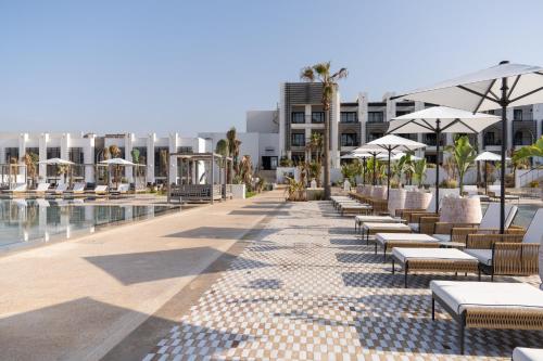 a resort with a pool and tables and umbrellas at Sofitel Agadir Thalassa Sea & Spa in Agadir