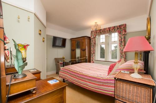 a bedroom with a bed with a red lamp and a window at Chestnut Grove Bed And Breakfast in Norwich