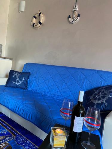 a blue couch with two glasses of wine on a table at Azul - privacy tranquillità natura e mare in Rosolina Mare