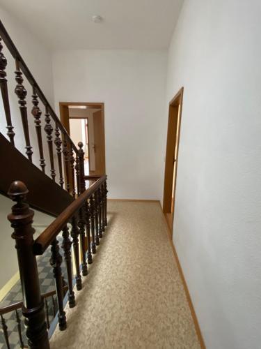 a hallway with a stairway with a wooden railing at Ferienwohnung H&M Immobilien Alsleben 1 in Alsleben