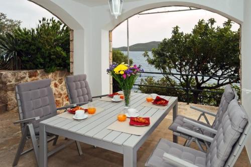 uma mesa branca com um vaso de flores em Holiday Home Odiseja em Slano