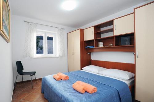 um quarto com uma cama azul e 2 toalhas cor de laranja em Holiday Home Odiseja em Slano