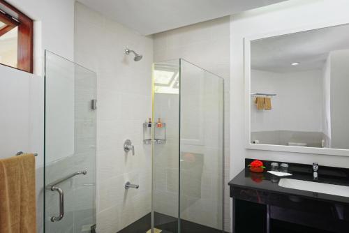 a bathroom with a glass shower and a sink at Embudu Village Resort in South Male Atoll