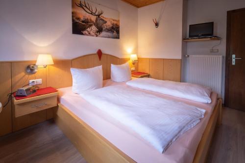 een slaapkamer met een groot bed met witte lakens bij Pension Villa Lockstein in Berchtesgaden