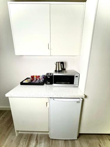 a kitchen with white cabinets and a microwave on a counter at Axiom Park Hotel in London