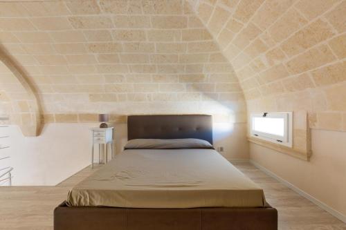 1 dormitorio con 1 cama en una pared de ladrillo en Dimore Bonafede by BarbarHouse, en Maruggio