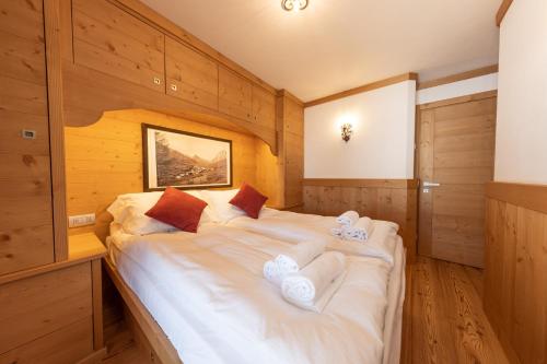 un grande letto bianco in una stanza con pareti in legno di Cadin Apartment a Cortina dʼAmpezzo