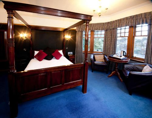 1 dormitorio con cama con dosel, silla y mesa en Rivendell, en Dumfries