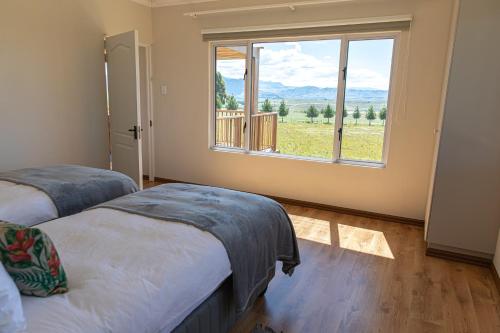 a bedroom with two beds and a large window at Dragons Landing Cottage in Underberg