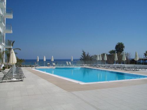 una grande piscina con sedie e ombrelloni di A209 Coralli Spa, Cyprus - Med View Studio a Protaras