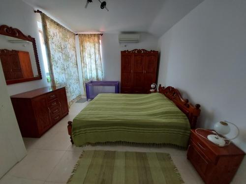 een slaapkamer met een groen bed en houten meubilair bij Kapriz Apartment in Kiten