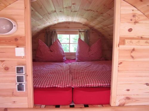 ein Bett in einem kleinen Zimmer in einem winzigen Haus in der Unterkunft Schlaffass-Camping Gutshof Donauried in Günzburg