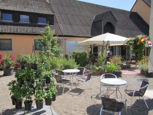 a courtyard with tables and chairs and potted plants at Schlaffass-Camping Gutshof Donauried in Günzburg