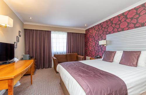 a hotel room with a bed and a desk at Mercure Tunbridge Wells Hotel in Royal Tunbridge Wells