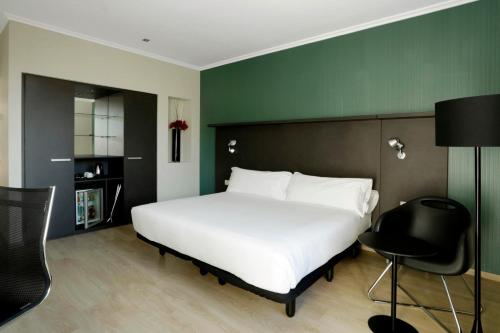 a bedroom with a large white bed and a green wall at Hotel Alimara in Barcelona