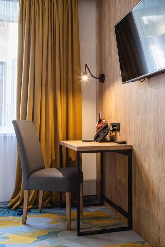 a desk with a chair and a television on a wall at Optima Collection Mural Lviv in Lviv