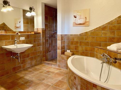 a bathroom with a bath tub and a sink at Hotel Sonnenhof Aspach in Aspach