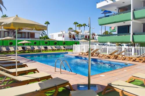 a swimming pool with lounge chairs and a hotel at Dunaoasis Maspalomas in Maspalomas