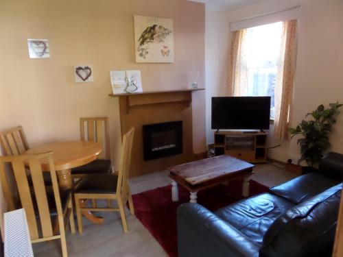 a living room with a couch and a table and a fireplace at Jane's Cottage Free Parking in Inverness