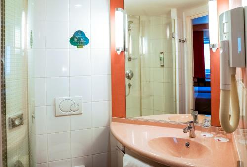 a bathroom with a sink and a shower with a mirror at Ibis Győr in Győr