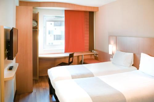 una camera d'albergo con due letti e una finestra di Ibis Győr a Győr