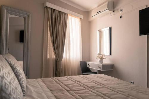 een slaapkamer met een bed, een bureau en een raam bij Remvi Deluxe Apartment 104 with Sea View in Karpathos