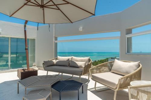 a patio with a couch and chairs and an umbrella at Hotel Brisa Praia Pajuçara in Maceió