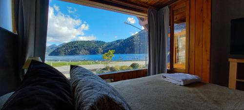 a bedroom with a large window looking out at the water at Cabañas Del Lacar in San Martín de los Andes