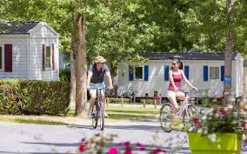 a man and a woman riding bikes in front of a house at Bungalow charmant Onzain + Piscine in Onzain