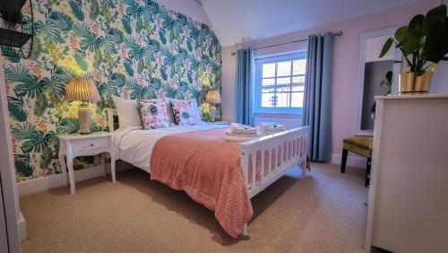 una camera da letto con un letto e carta da parati floreale di The Angel Holiday House a Warminster