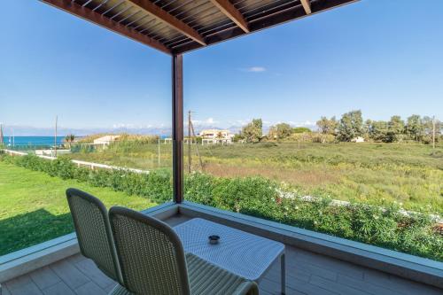 a balcony with a table and chairs looking out at a field at Almyros Beach in Acharavi