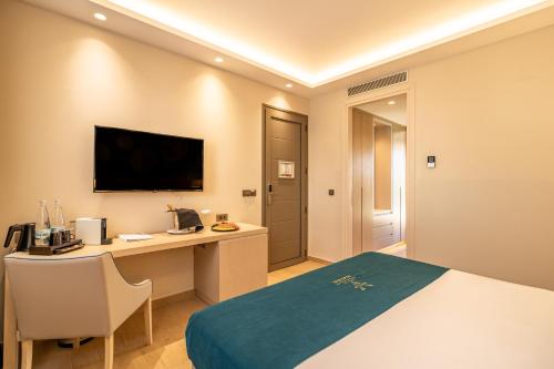 a hotel room with a bed and a desk and a television at Almyros Beach in Acharavi